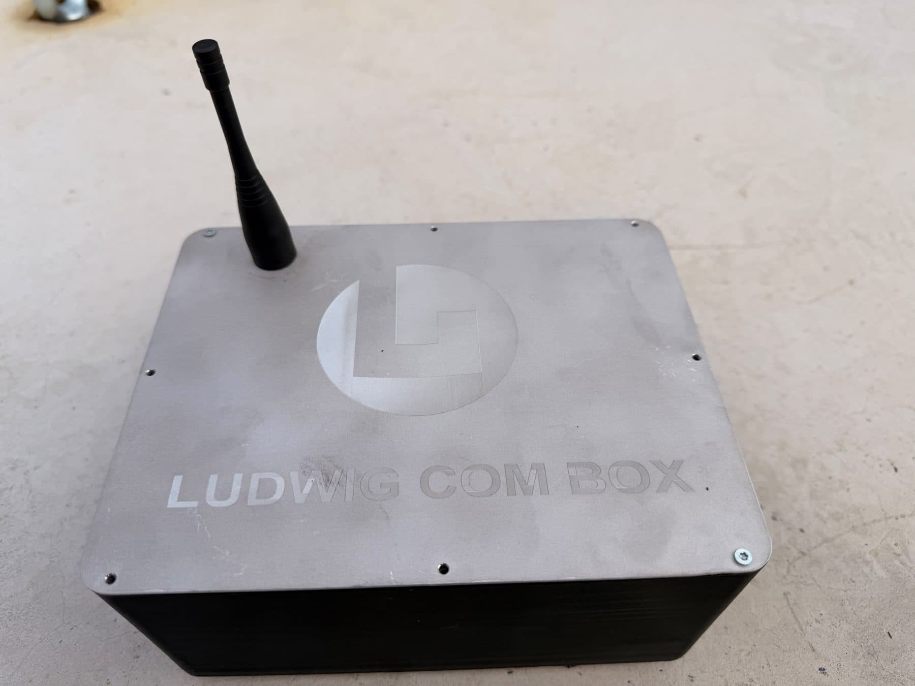 Ludwig COM Box, ein Metallgehäuse mit gravierter Aufschrift und Antenne