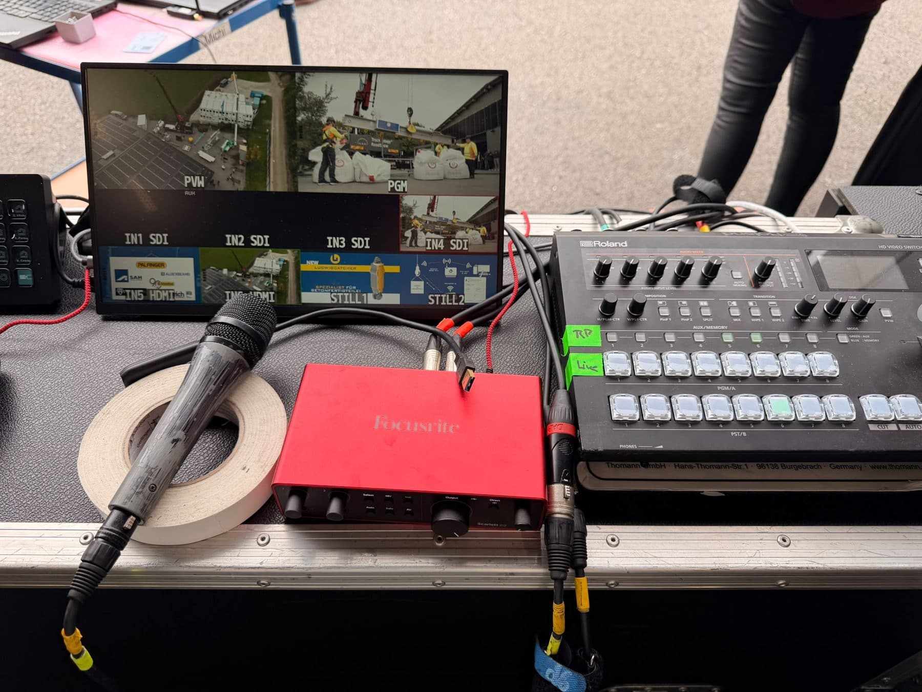 Roland-Videomischer, Focusrite-Audio-Interface und Handmikrofon vor dem Multiview-Monitor